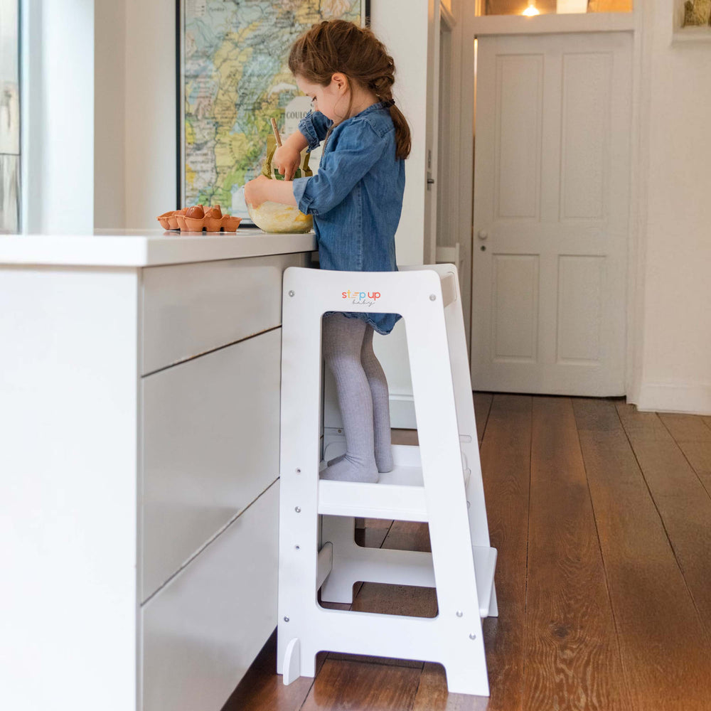 Side view of toddler standing securely in Stepup Toddler Tower while cooking.